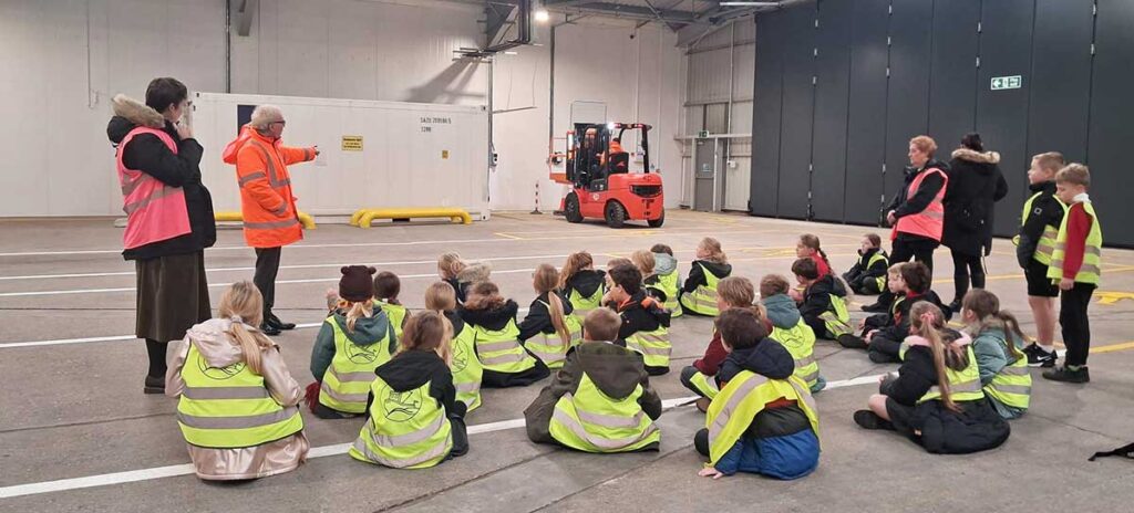 Harbour Primary School pupils seated on the floor and listening to a talk at Newhaven port in the Border Control area