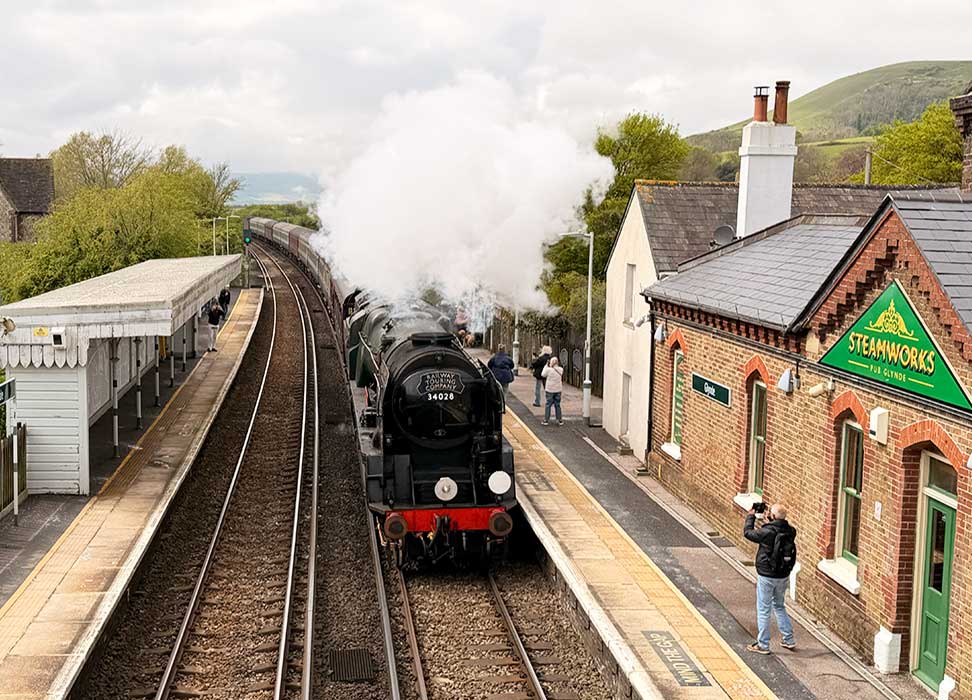 steam train at full steam travelling through Glynde Station, Sussex